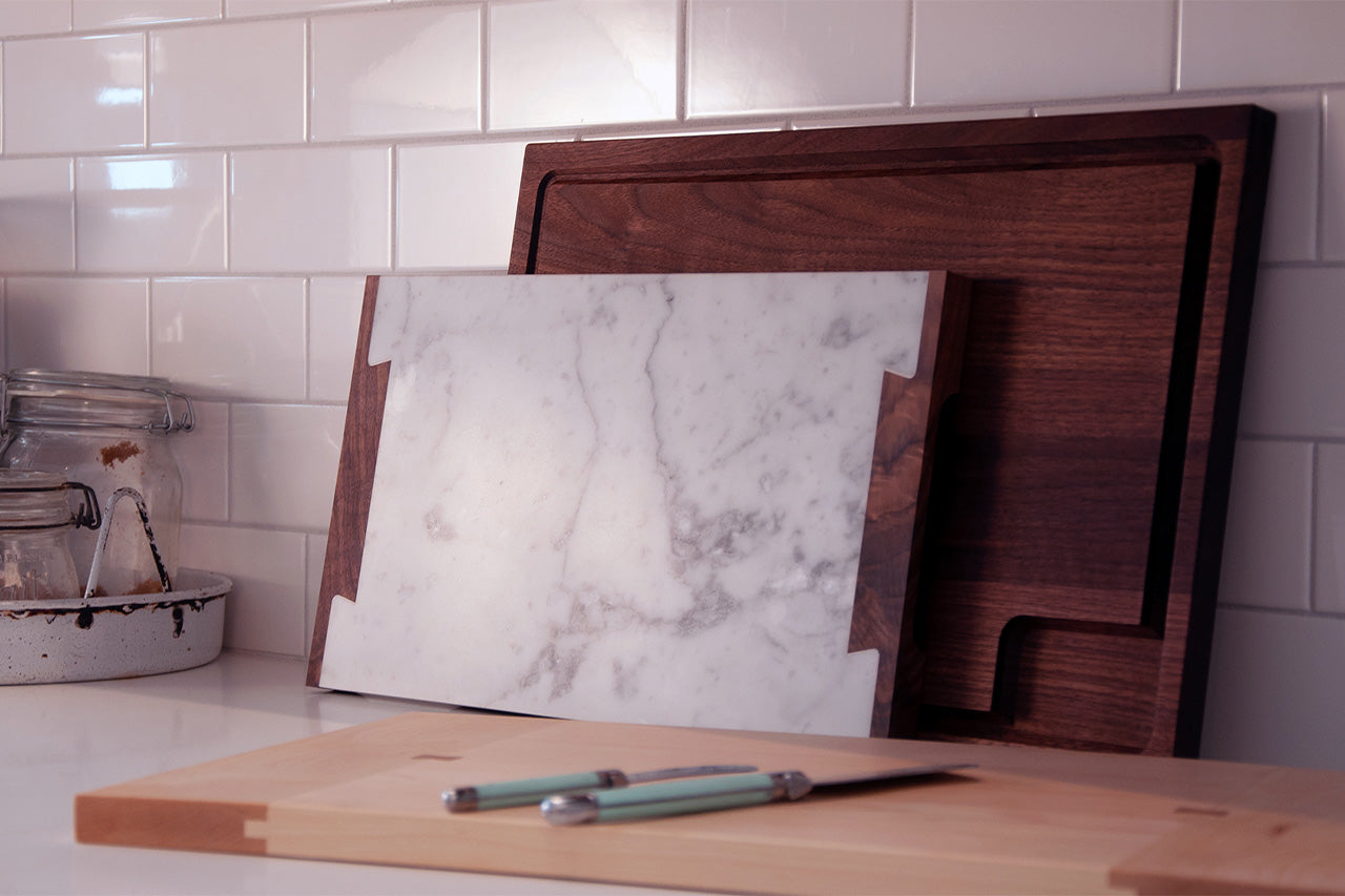 carrara marble and walnut serving board in kitchen with white subway tiles
