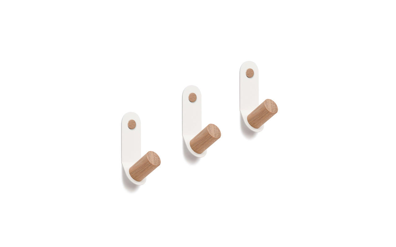 Three Plane Single Hooks - Set of 3 by Fire Road made of powder-coated steel with white bases and wooden pegs are arranged in a row against a white background.