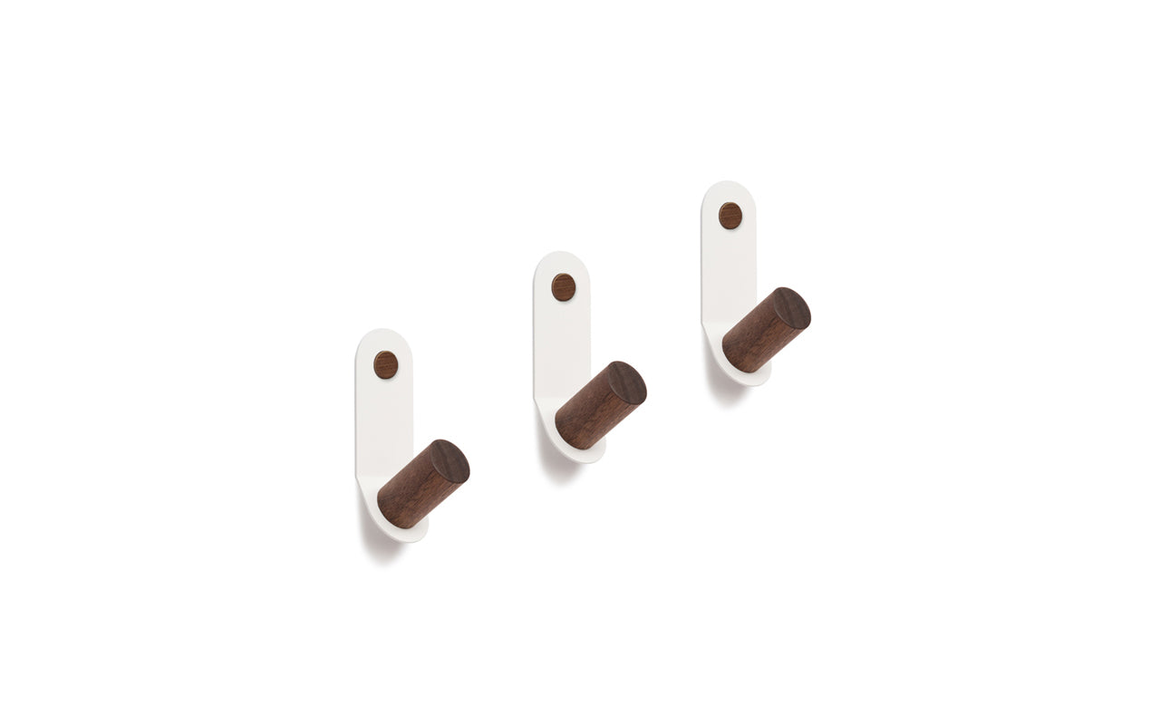 Three Plane Single Hooks - Set of 3 from Fire Road, with white, powder-coated steel bases and cylindrical wooden pegs, are arranged in a straight horizontal line.
