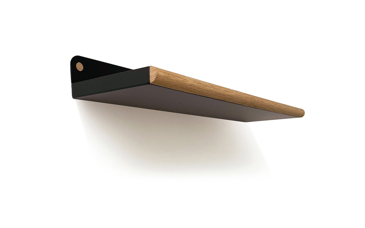 A minimalist Fire Road Plane Wall Shelf with a black base and walnut wood front edge is mounted on a white wall.