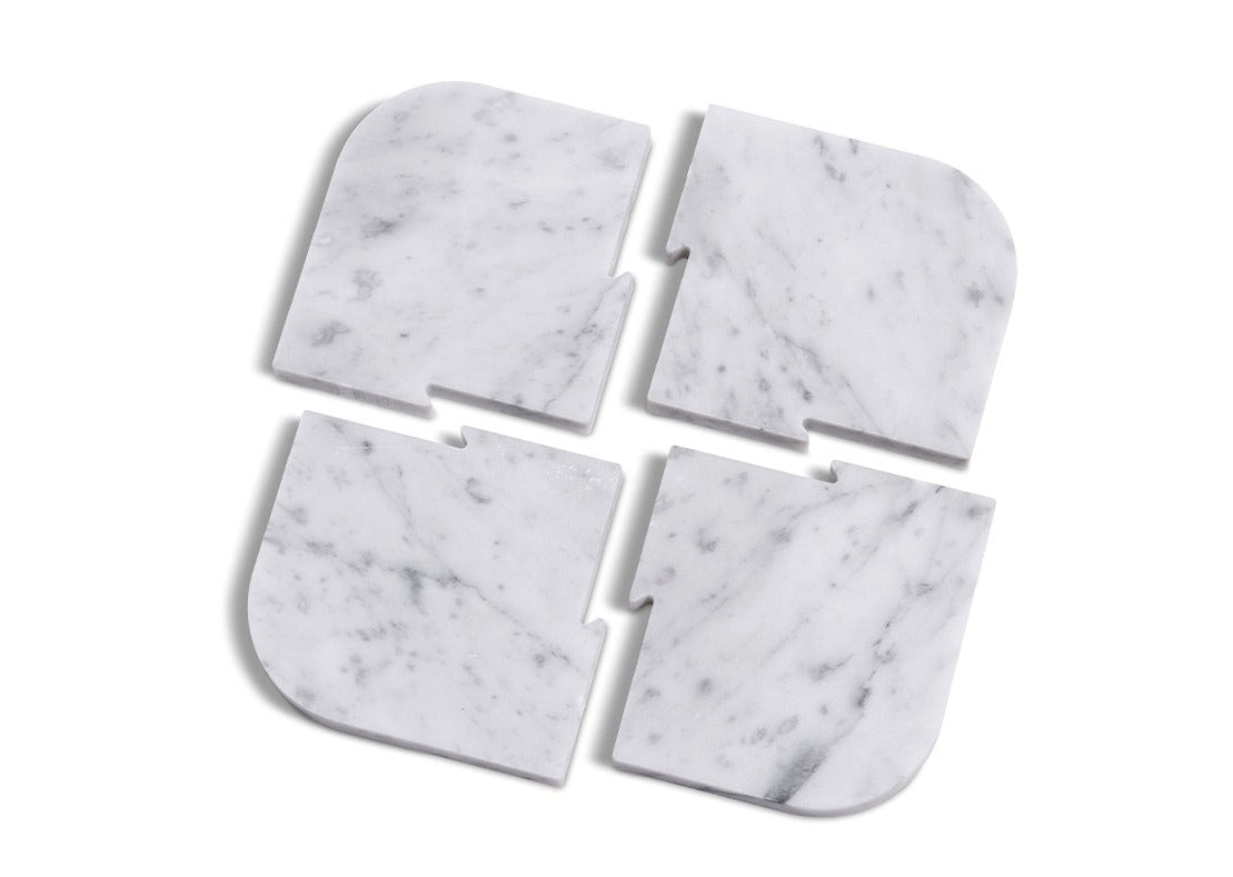 Four pieces of the Fire Road Bar Set, made of white marble, on a white surface, perfect for coasters or as a bottle opener.