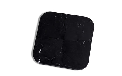 A black Join Coasters + Trivet plate on a white surface by Fire Road.
