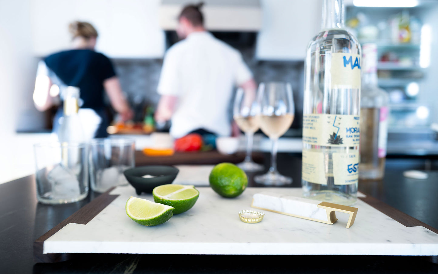 A Fire Road Profile Bottle Opener and limes on a tray in a kitchen with a wooden handle.