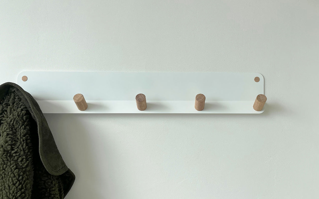 A white Fire Road Plane 5 Wall Hook with four wooden pegs/hooks for coat hanging.